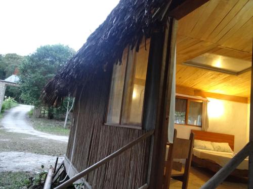 a straw hut with a bed and a window at Tres Lagunas, Selva Lacandona in Lacanjá