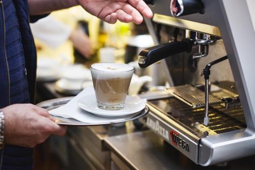 a person is making a cup of coffee on aucer at Hotel U Zlateho jelena in Prague