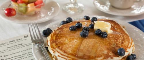 Un plato de panqueques con arándanos y mantequilla y un tazón de fruta. en Beech Tree Inn and Cottage, en Newport