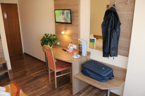 Zimmer mit einem Schreibtisch und einer Tasche darauf in der Unterkunft Hotel Brigitte in Bad Krozingen