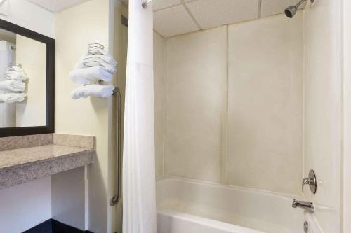 a bathroom with a shower and a tub with towels at Heritage Inn Augusta in Augusta