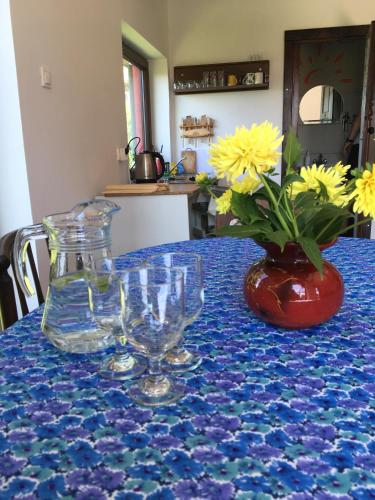 a table with glasses and a vase with yellow flowers at Chata nad Wisłą u Macieja in Dobrzyków
