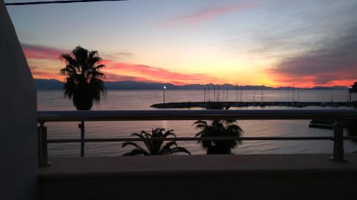a sunset from a balcony with a view of the water at Onar Corfu Aparts & Studios in Ýpsos