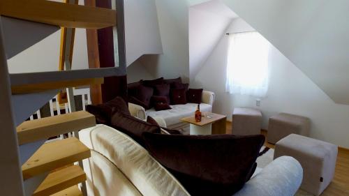 uma sala de estar com um sofá e cadeiras e uma escadaria em Dobricin Konak Apartments em Kopaonik