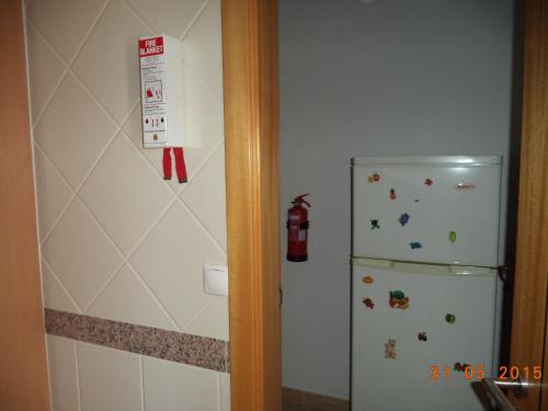 a kitchen with a refrigerator and a fire extinguisher on the wall at St James Apartment in Luz