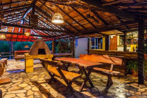 eine Terrasse mit einem Tisch, Bänken und einer Hängematte in der Unterkunft Pousada Casa da Moeda in Brumadinho