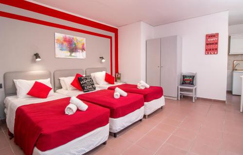 una camera con due letti con lenzuola rosse e bianche di Kahlua Hotel Apartments a Città di Rodi