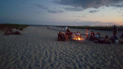 a group of people sitting around a bonfire on the beach at Blue Sea Motor Inn in North Truro