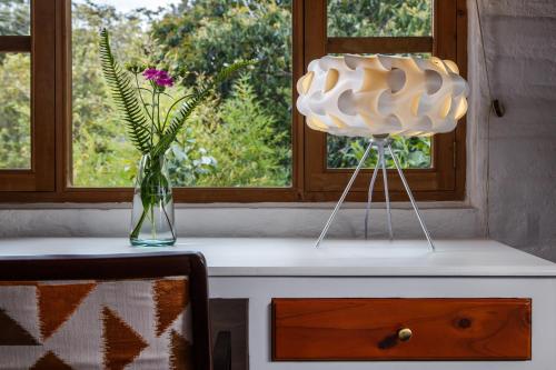 a table with a vase of flowers and a window at Rukka Lodge in Tumbaco