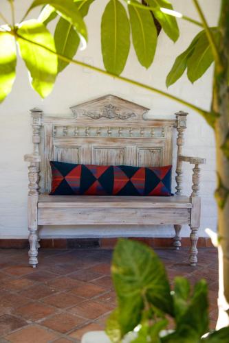 a wooden bench with a red and blue pillow on it at Rukka Lodge in Tumbaco