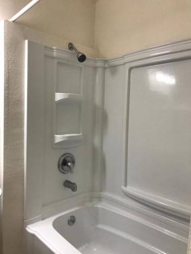 a white bath tub with a shower in a bathroom at Townhouse Motel in Weed