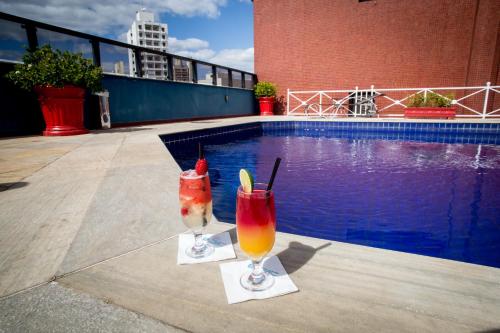 two cocktails sitting on a patio next to a swimming pool at Hotel Dan Inn Campinas Cambuí - Um Hotel Clássico Em Campinas in Campinas