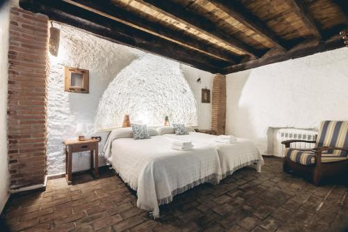a bedroom with a white bed in a brick room at Casas Cueva Tio Tobas Guadix in Alcudia de Guadix