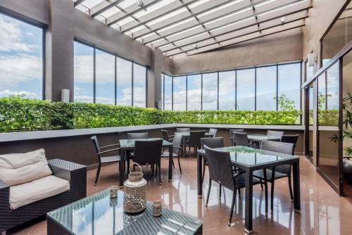 a restaurant with tables and chairs and windows at Wyndham Garden San Jose Escazu, Costa Rica in San José