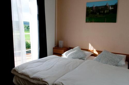 Schlafzimmer mit einem Bett mit weißer Bettwäsche und einem Fenster in der Unterkunft Hotel Restaurant Vijlerhof in Vijlen