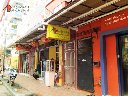 a row of buildings on a street with a person sitting on aooter outside at Sandakan Backpackers Hostel in Sandakan