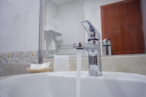 a bathroom sink with a faucet in front of a mirror at Gran Mundo Hotel & Suites in Lima