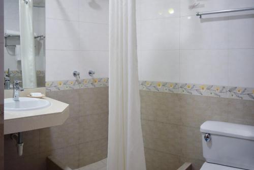 a bathroom with a toilet and a sink and a shower at Gran Mundo Hotel & Suites in Lima