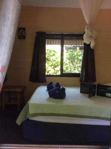 a bedroom with a bed with blue pillows and a window at Seetanu Bungalows in Srithanu