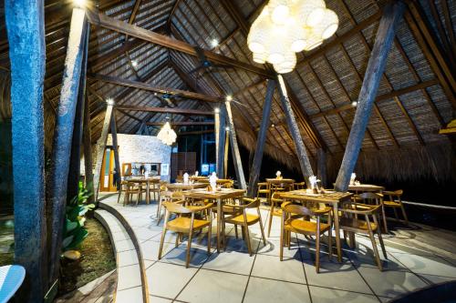 a restaurant with wooden tables and chairs in a building at C-View Villas in Nusa Lembongan