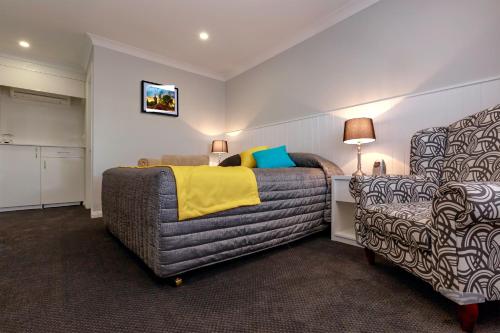 1 dormitorio con 1 cama y 1 silla en Oasis Motel, en Cobar