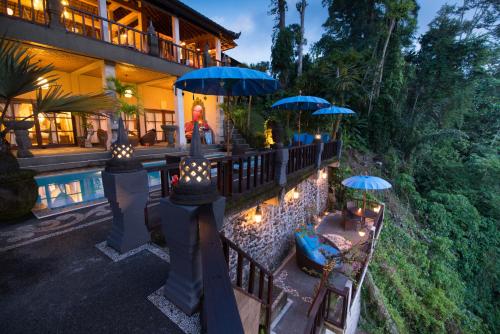 uma casa com piscina, guarda-sóis e cadeiras em Villa Kalisat Resort em Ubud