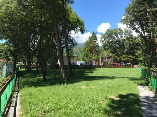a park with trees and a green fence at DogrunCafe & Resorts JENNIE West-Karuizawa in Miyota