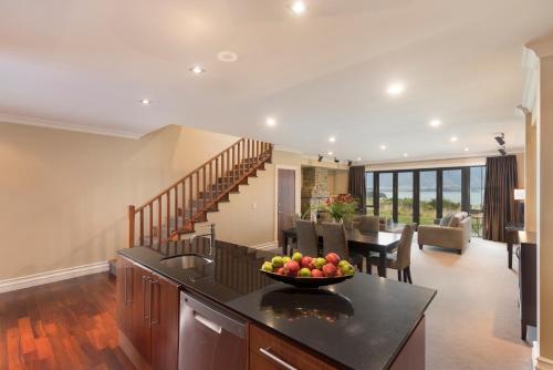 a kitchen and living room with a bowl of fruit on a counter at Platinum Queenstown in Queenstown