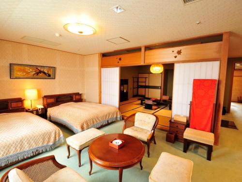 a hotel room with two beds and a table and chairs at Nisshokan Bettei Koyotei in Nagasaki