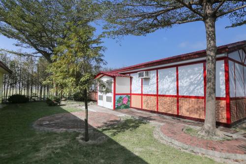 白河區的住宿－長奕雅築，一座红白色房子,在院子里种有树木
