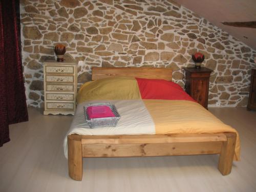 a bedroom with a wooden bed and a stone wall at La Croix De Camargue in Oradour-sur-Glane