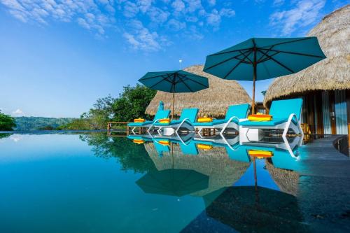 a resort with chairs and umbrellas on the water at C-View Villas in Nusa Lembongan