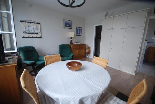 un salon avec une table et des chaises blanches dans l'établissement Le quai Maupassant, à Fécamp