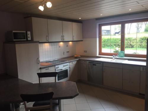 a kitchen with white cabinets and a table and a window at Eifelferienhaus Pruem in Steinmehlen