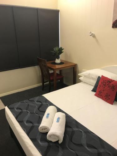 a bedroom with a bed with two towels on it at Parkside Motel Ayr in Ayr
