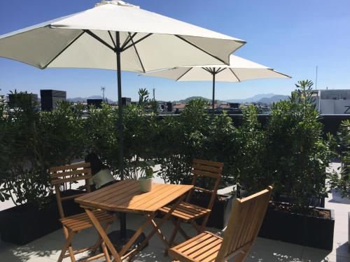 a wooden table with two chairs and an umbrella at Talo Urban Rooms in Donostia-San Sebastián