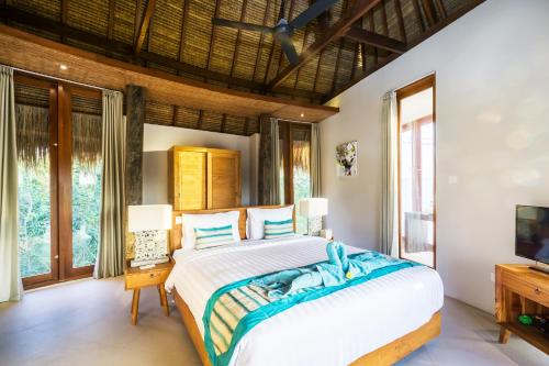 a bedroom with a large bed and a tv at C-View Villas in Nusa Lembongan
