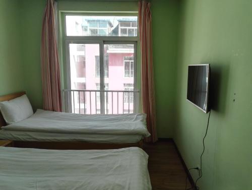 two beds in a room with a window and a television at LETE Hostel in Xining