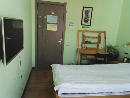a room with a bed and a table and a door at LETE Hostel in Xining