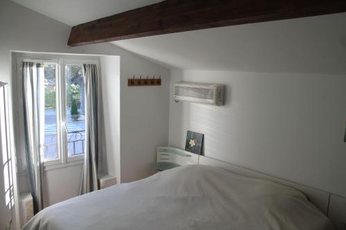 ein weißes Schlafzimmer mit einem Bett und einem Fenster in der Unterkunft Maison Sous les Platanes in Saint-Pantaléon-les-Vignes
