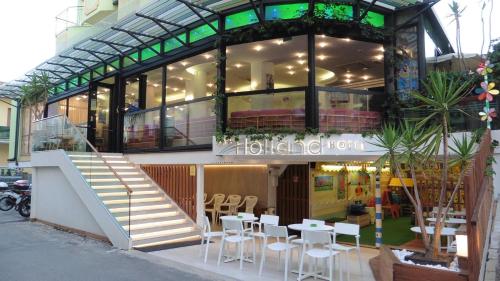 a building with white tables and chairs in front of it at Hotel Holland in Rimini