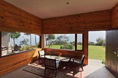 a dining room with a table and chairs and windows at Cedar Lodge By Aahma in Rāmgarh