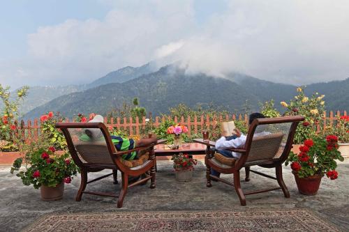 two people sitting at a table with a view of a mountain at Cedar Lodge By Aahma in Rāmgarh