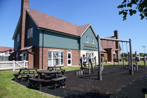 a playground with picnic tables in front of a building at Blue Jay, Derby by Marston's Inns in Derby