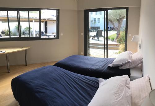 Cette chambre dispose de 2 lits, d'un bureau et de fenêtres. dans l'établissement L'Île de Lumière, à Rivedoux-Plage