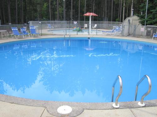 a large blue swimming pool with chairs and an umbrella at Yukon Trails Camping Resort in Lyndon Station