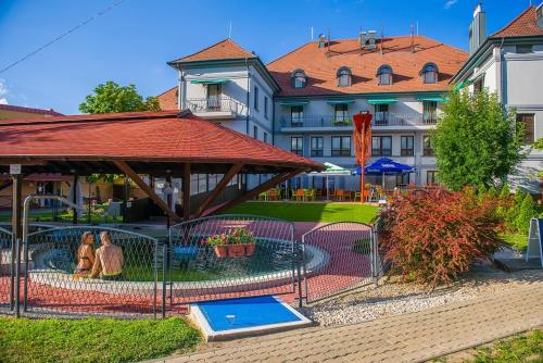 a bird cage with two people in it next to a building at Hotel Kamilla in Balmazújváros