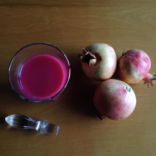 a cup of pink liquid next to three pomegranates at Azienda Agricola Il Querceto in Marsico Vetere