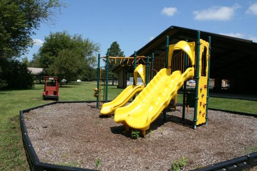 a playground with a yellow slide in a park at Pine Country Camping Resort in Belvidere