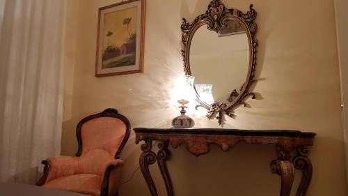 a table with a mirror and a chair and a lamp at Gran Suite Piazza Maggiore - T&T communications in Bologna
